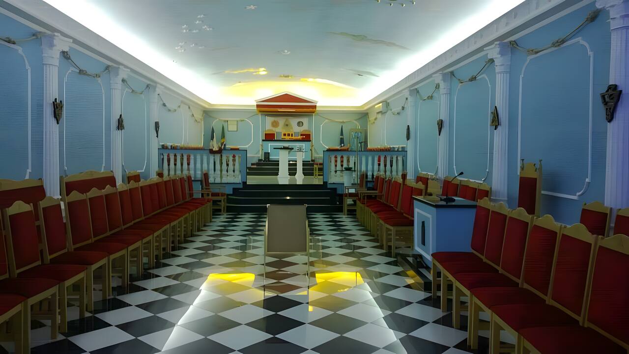 O templo da Loja: paredes azul-celeste, cadeiras de veludo vermelho, piso mosaico e o Oriente ao fundo